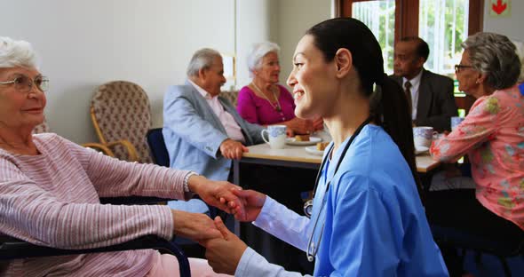 Side view of Caucasian female doctor consoling sad disabled senior woman at nursing home 4k