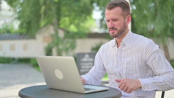 Middle Aged Man with Laptop Having Back Pain Outdoor