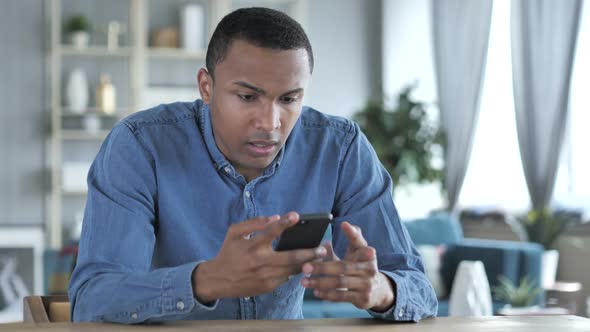 Young African Man Upset for Loss While Using Smartphone