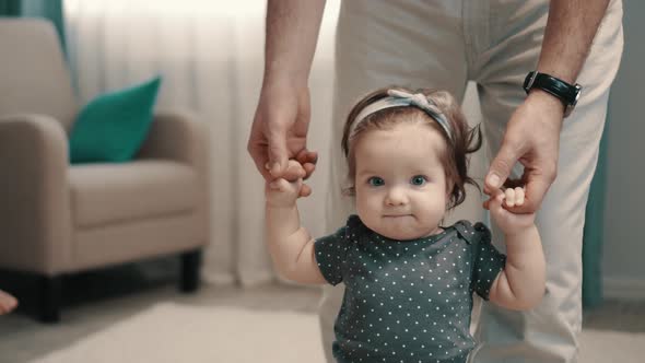Little Girl Takes Her First Steps with Help of Her Father