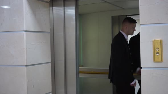 Confident Handsome Young Businessman Entering Elevator Pressing Button and Lift Door Closing