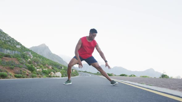 African american man performing stretching exercise on the road