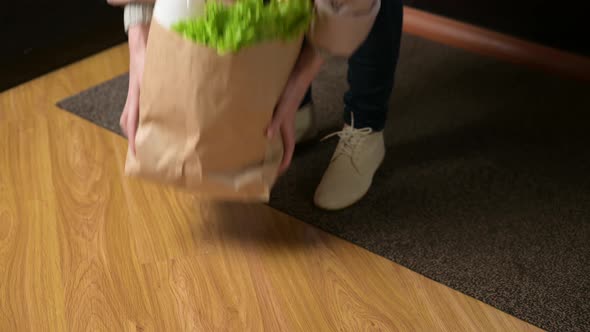 A bag of food falls when a woman places it on the floor