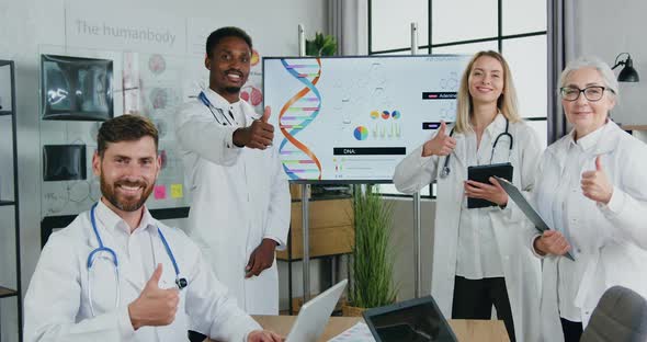 Doctors Posing on Camera in Clinic Office and Gesturing Thumbs Up