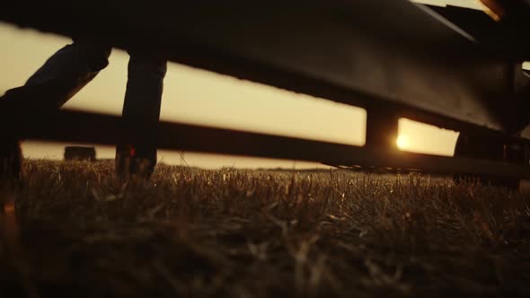 Farmer Boots Walking Wheat Field Machinery at Golden Sunset