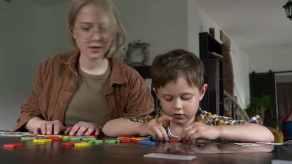 Mom teaches her son how to say the words on the cards at home at the table