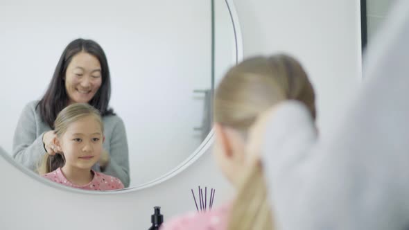 Mother doing daughter's hair