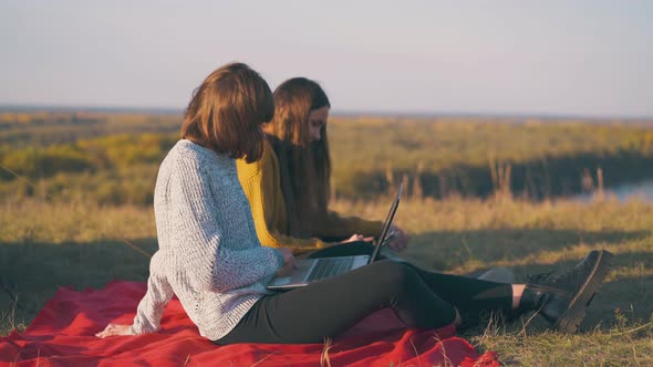Women Use Tablet and Laptop Sitting on Red Plaid in Camp