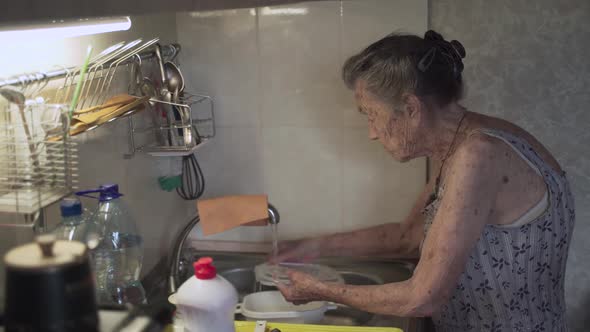 Senior Elderly Woman Washing Dishes in Kitchen