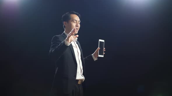 Side View Of Asian Speaker Man In Business Suit Holding And Pointing Tablet While Speaking