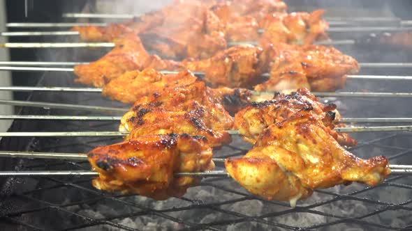 Barbeque chicken tikka roasting on glowing coals 