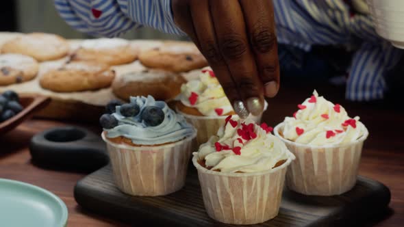 African American Chef Decorating Cupcakes with Berries and Confetti Closeup