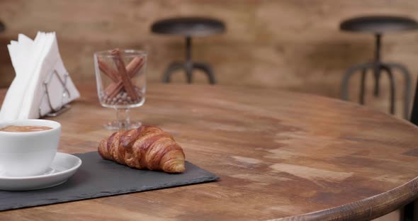 Revealing Shot of a Fresh Cup of Black Coffe with a Delicious Croissant