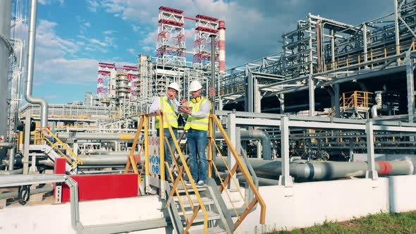 Oil Refinery Premises with Engineers Talking to Each Other