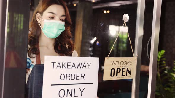 Business owner attractive young asian woman in apron hanging we're open sign.