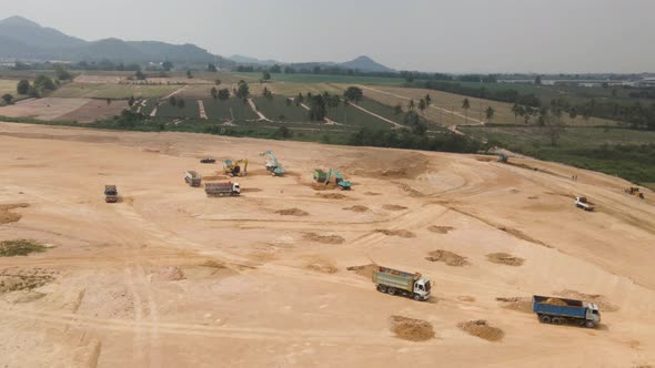 Aerial of Trucks loaded with sand on Construction site, Excavators digging the soil, Aerial Orbiting