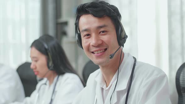 Man Doctor Wearing Headsets Working As Call Centre Agent Look Up, Smile, And Thumbs Up