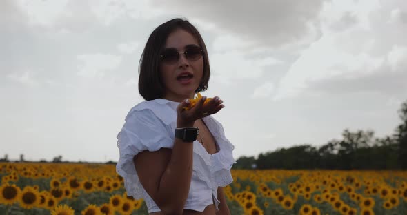 Beautiful Woman Blowing Petals in Sunflower Field