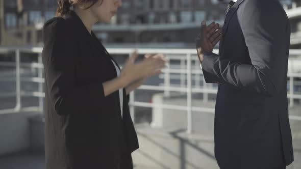 Unrecognizable Multiracial Coworkers Arguing Outdoors in Sunlight. Young Angry Caucasian Woman and