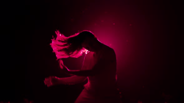 Young Woman Moves Her Head and Hair in Dark Studio