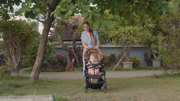 Mother Pushing Stroller with Happy Baby