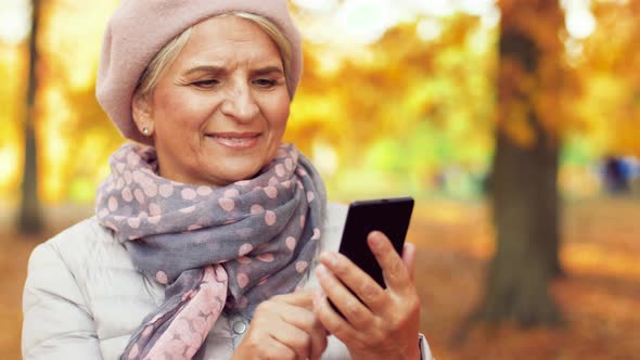 Happy Senior Woman with Smartphone at Autumn Park 14