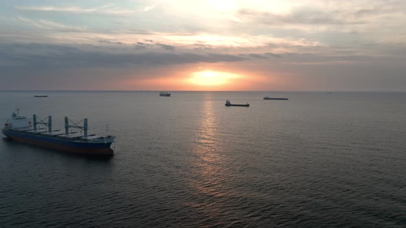 A drone flight around container ships into the sea at sunrise