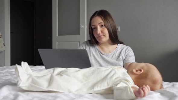 Mother Pays Attention to Baby Girl While Working on Laptop