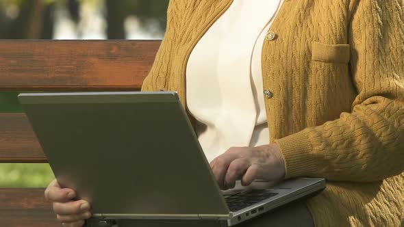 Smiling Retired Lady Slowly Typing Laptop, Resting Outside, Browsing Internet