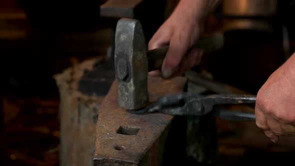 Blacksmith Beating Hot Iron with Hammer on an Anvil