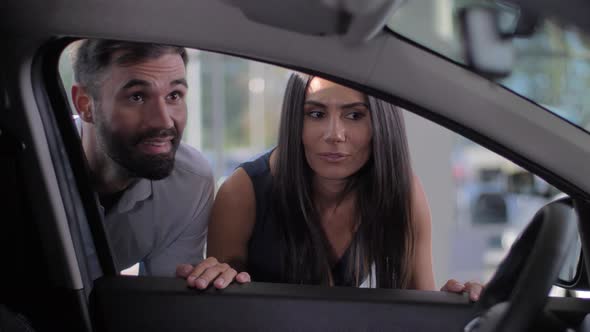 Happy Couple Looking Inside Car in Dealership