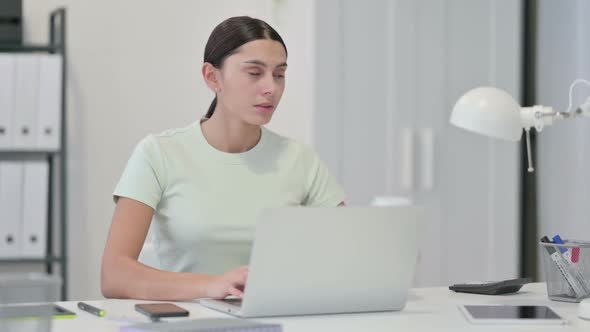 Young Latin Woman Drinking Coffee and Working on Laptop