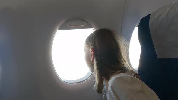 Cute Teenage Girl Sitting in Airplane and Looking at Window