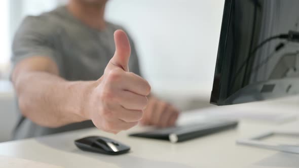 Young Man Showing Thumbs Up While Using Desktop Close Up