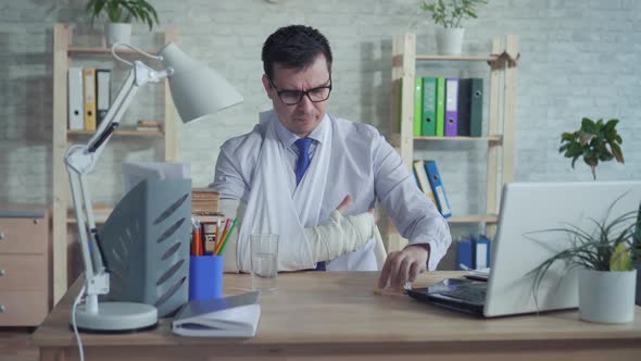 Man Office Worker with Broken Arm Drinking Medicine