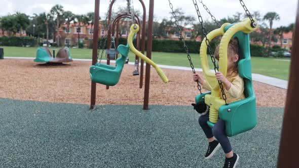 Slow Motion of Little Girl Swinging at Infant Swing at Playground