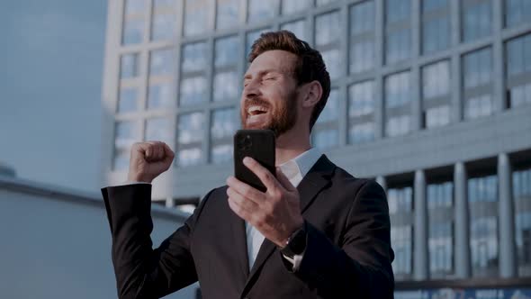 Successful Confident Businessman with a Phone Celebrates His Success