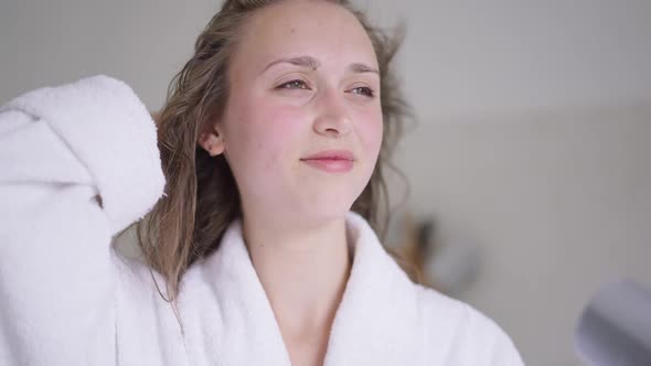 Closeup Portrait of Happy Smiling Young Beautiful Woman Drying Hair in Slow Motion with Hair Dryer