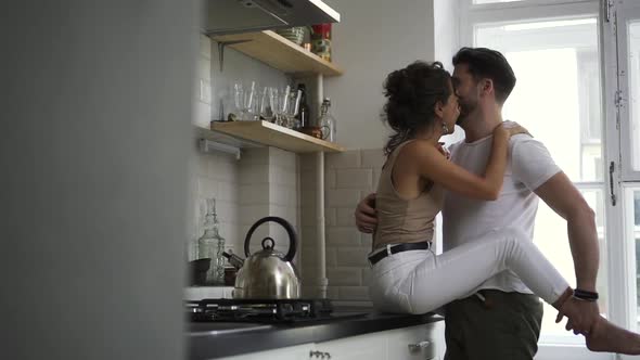 Couple in the Kitchen the Girl Sits on the Table and the Guy Gently Hugs Her and They Kiss Spbd