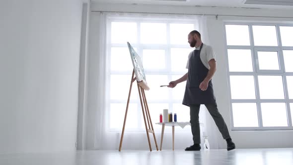 The Artist Paints an Abstract Picture He is Focused on Work Painting on an Easel in His Art Studio