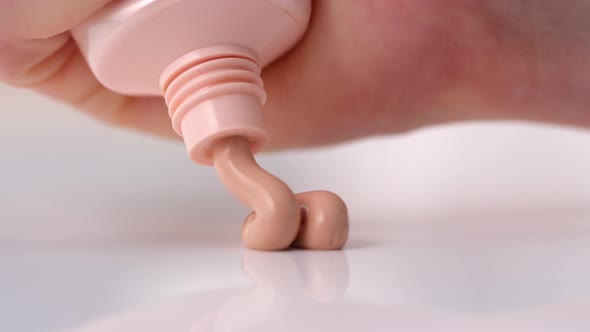 Close Up View of Squeezing Makeup Foundation on Table