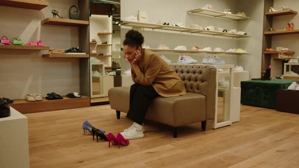 AfricanAmerican Woman is Sitting in a Shoe Store and Cannot Choose