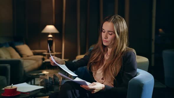 Serious Businesswoman Working with Documents in Hotel Lobby at Evening