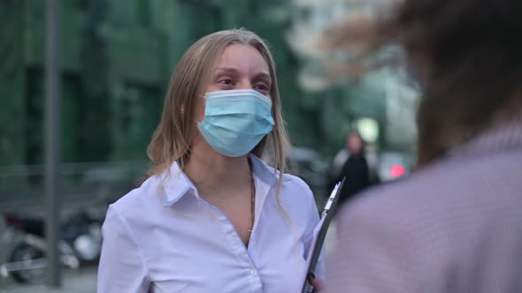 woman in medical mask after work discusses business with colleague on the street