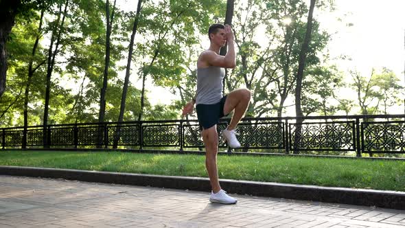 Muscular Man Warming Up with Back Lunge Exercise Outdoor Training