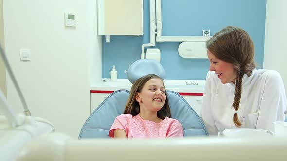 Smiling female dentist talking with lovely little girl