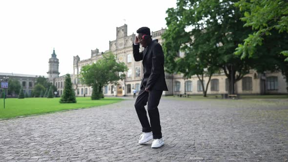 Wide Shot Relaxed African American Joyful Student in Formal Black Suit Dancing Listening to Music in