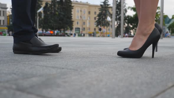 Feet of Businessman in Black Shoes and Businesswoman on High Heels Standing at City Street. Business