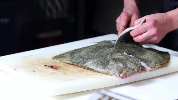 Fish vendor cutting a turbot for the clients, with black background