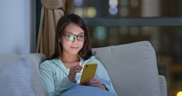 Woman with glasses and use of mobile phone at home in the evening